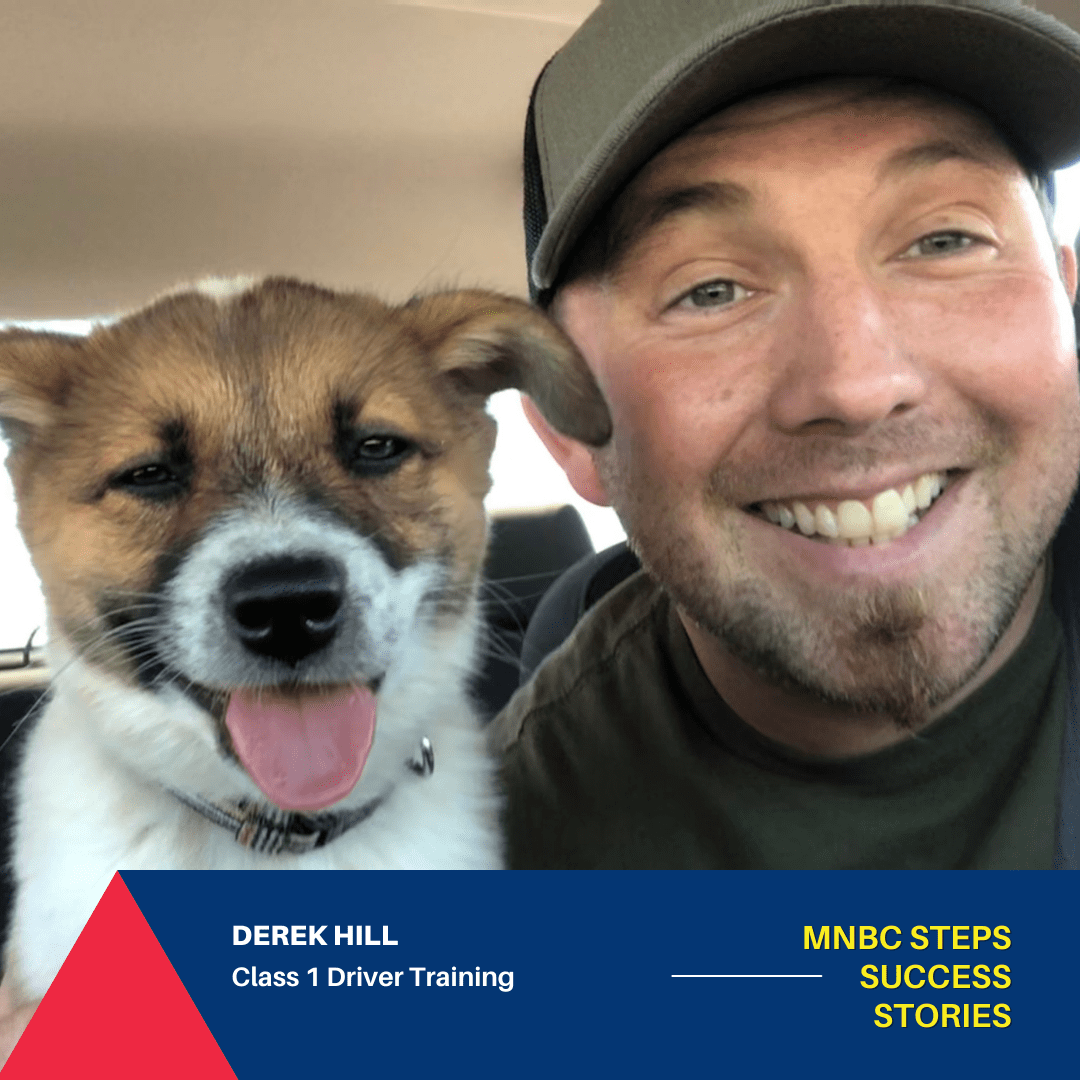 Derek Hill smiles directly at the camera next to a puppy with its tongue out.