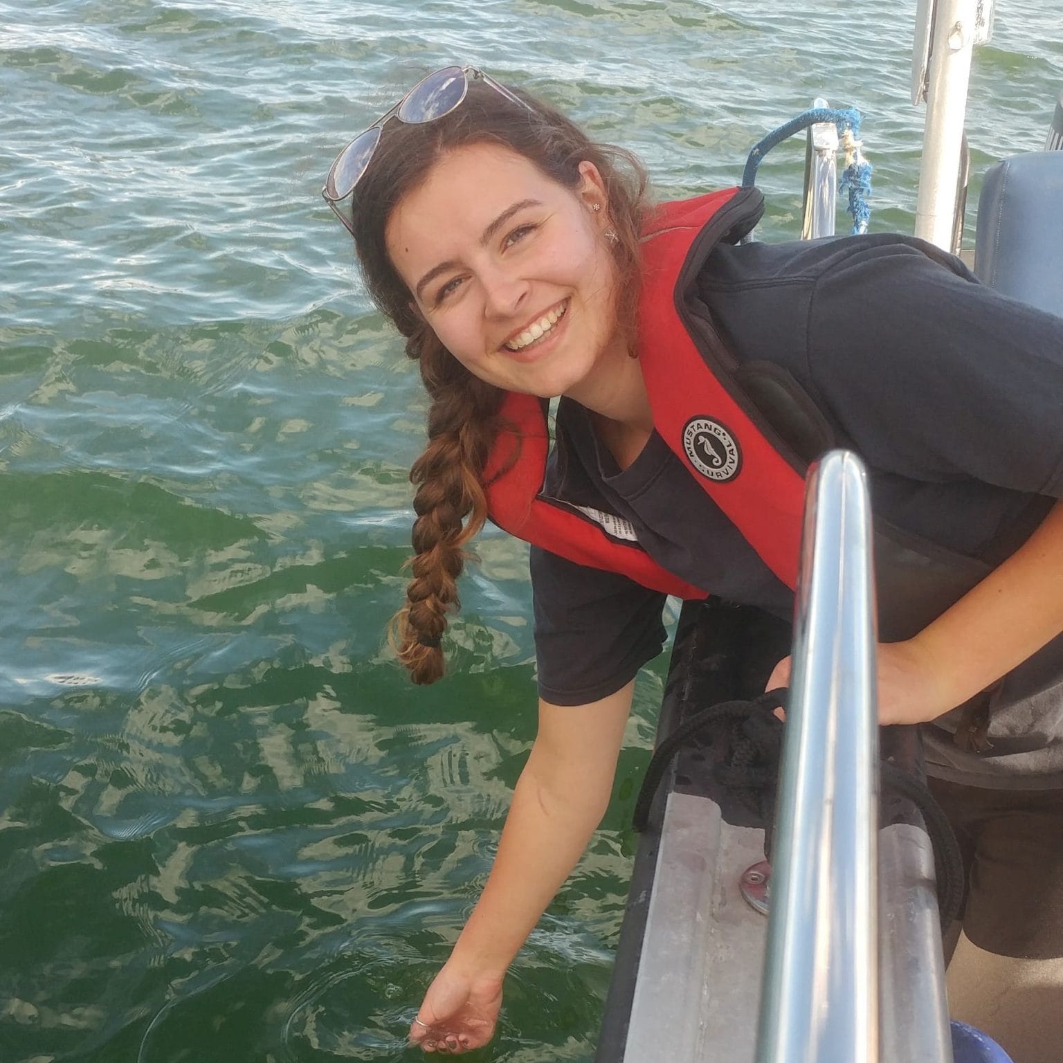 Jessica Schaub smiles at the camera, leaning over the side of a boat with her hand in the water.