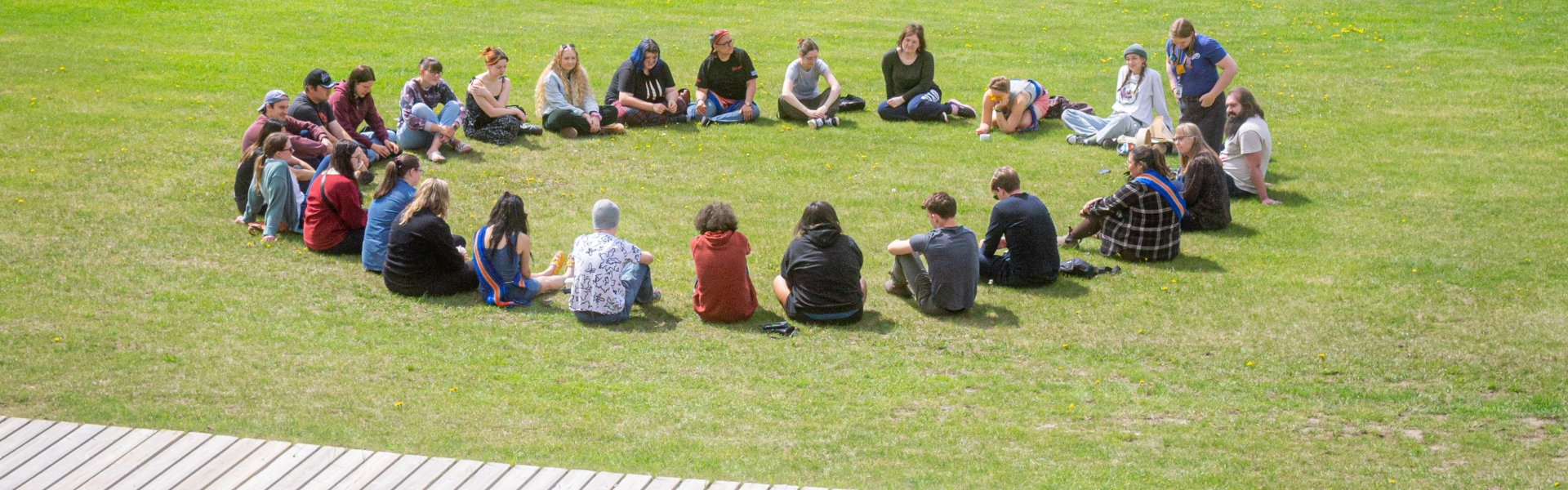 Group of young people sitting in a circle on the grass.