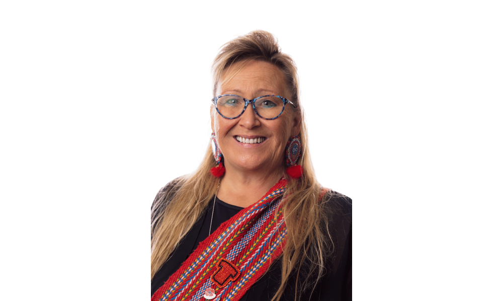 Headshot of a woman in glasses wearing a Metis red sash across her shoulder.