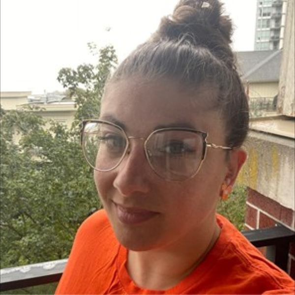 Image of a young woman with glasses and an orange tshirt.