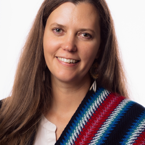 Headshot of a woman with long dark brown hair and a Metis sash over her shoulder.