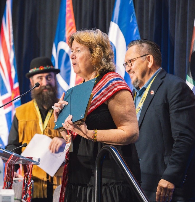 A woman stands at a podium accepting an award.