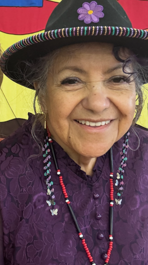 A smiling woman wearing a beaded black hat.