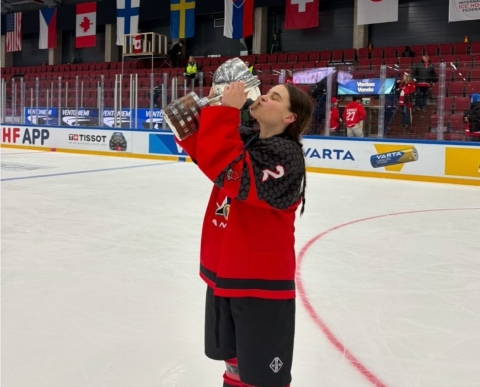 A female hockey player holds up the championship cup.