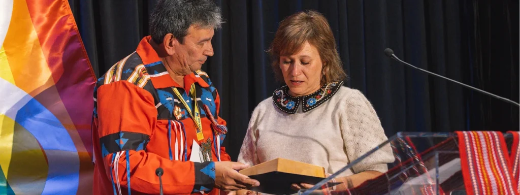 Two people are standing behind a podium presenting an award at a meeting.