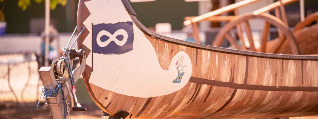 A close-up of the front of a wooden canoe with the Métis flag.